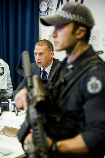 Detective sergeant Shane Scott addresses the media as an armed officer watches on. Photo: Jay Cronan