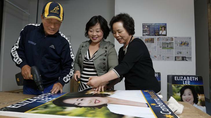 Elizabeth Lee, centre, with her parents John Lee and Cecilia Lee pull apart election placards at her city office. Photo: Jeffrey Chan
