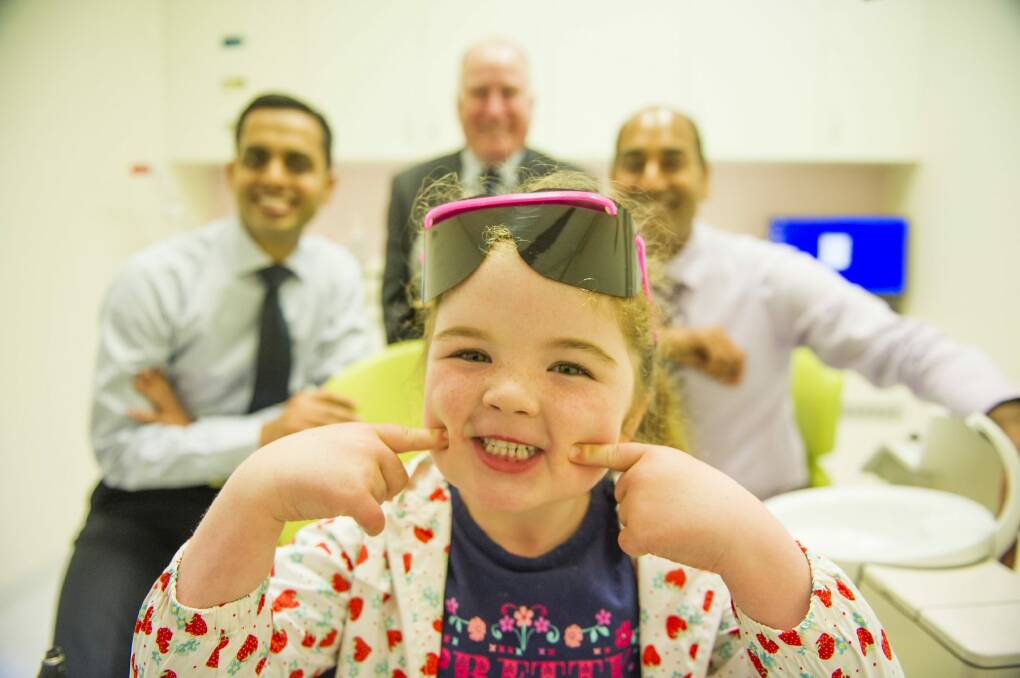 All smiles: Arabella Ferguson, 5, happy to be sitting in the dentist chair with dentists (left) Dr Sanjiv Pathak and (right) Dr Atul Manani with Minister Mick Gentleman at the newly open dental clinic at Calwell shopping centre. Photo: Jay Cronan