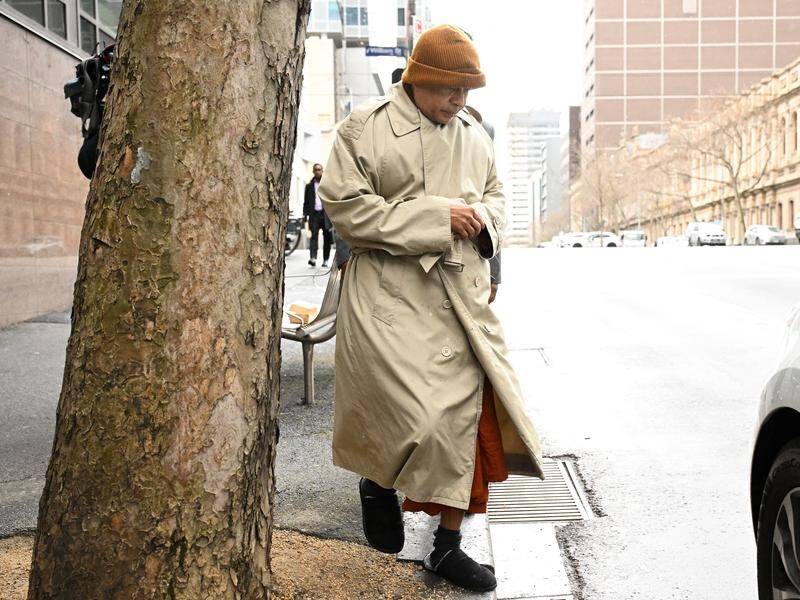 Vijitha Naotunne covered his robes with a trench coat and wore an orange beanie as he exited court. (James Ross/AAP PHOTOS)