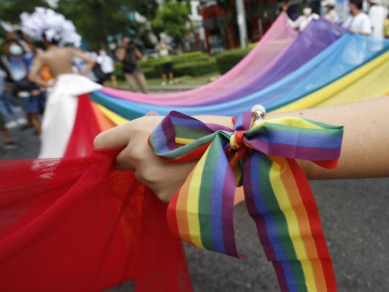 A Thai member of LGBT community ties a rainbow ribbon on her wrist during a parade. (EPA PHOTO)
