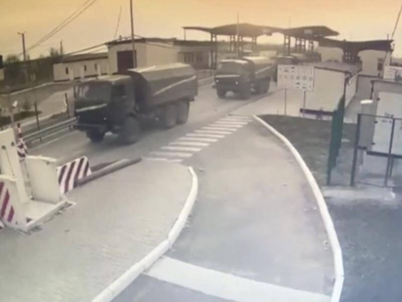 Russian military vehicles pass a control point at the Crimea border as Ukraine is invaded.