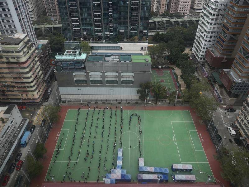 Hong Kong residents line up on a sports field to be tested for COVID-19.