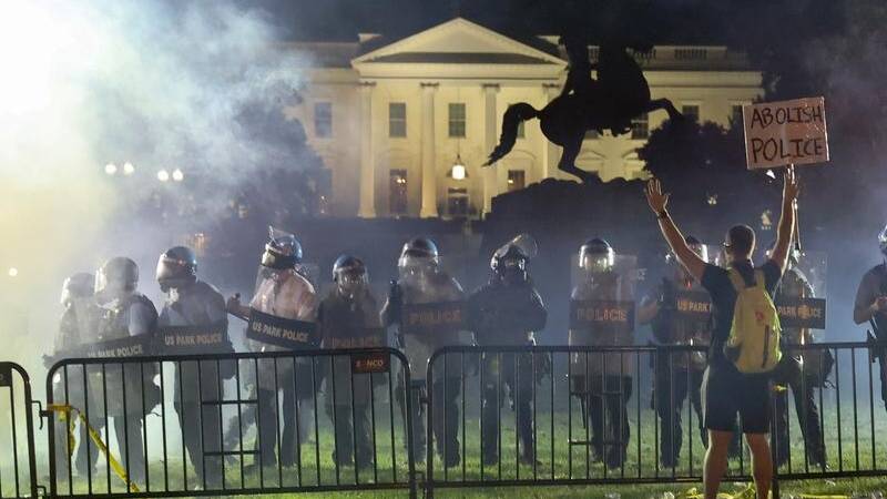 US police in riot gear keep protesters at bay in Lafayette Park near the White House.