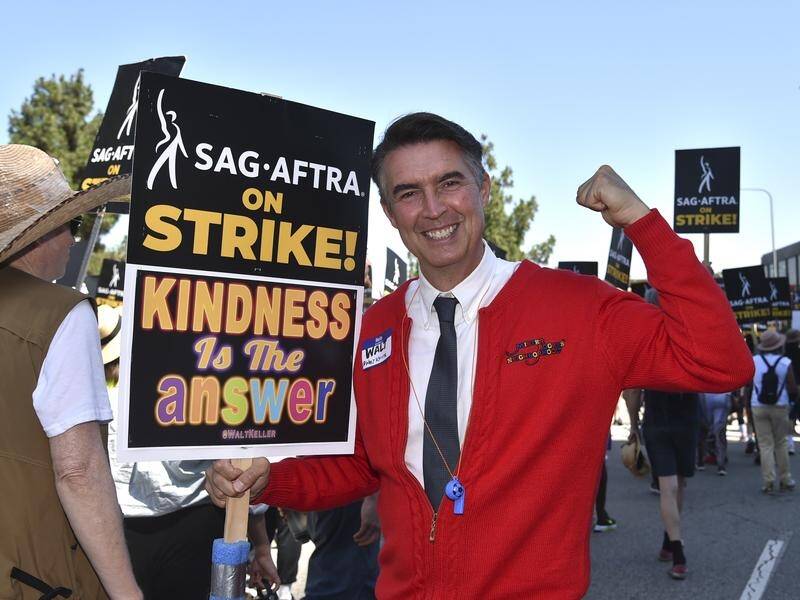 Actor Walt Keller dressed as Mister Rogers carries a picket sign outside Universal Studios. (AP PHOTO)