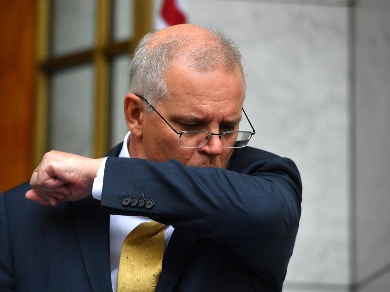 Scott Morrison coughs into his elbow at a press conference before being diagnosed with COVID-19.