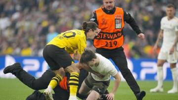Dortmund's Marcel Sabitzer tries to hold up a pitch invader. (AP PHOTO)