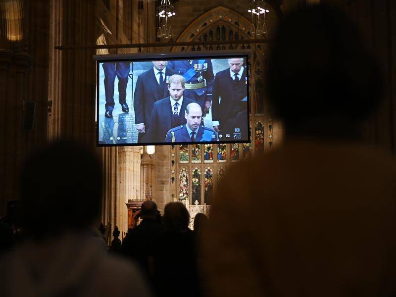 People watch a livestream of the Queen's state funeral from St Andrew's Cathedral in Sydney. (Steven Saphore/AAP PHOTOS)