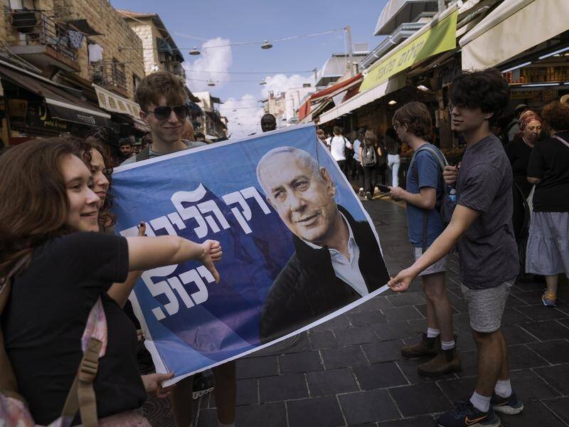 A woman gives the thumbs down to a banner depicting former Israeli PM Benjamin Netanyahu. (AP PHOTO)