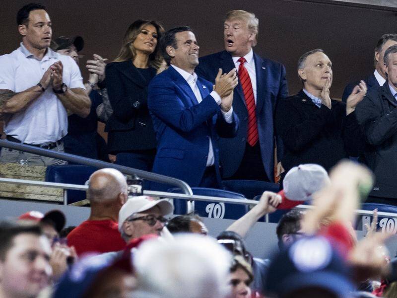 US President Donald Trump reacts as baseball fans boo him when he is shown on the big screen.