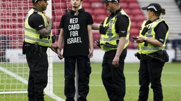 Police with a protester who had chained himself to a goalpost before Scotland's match with Israel. (AP PHOTO)