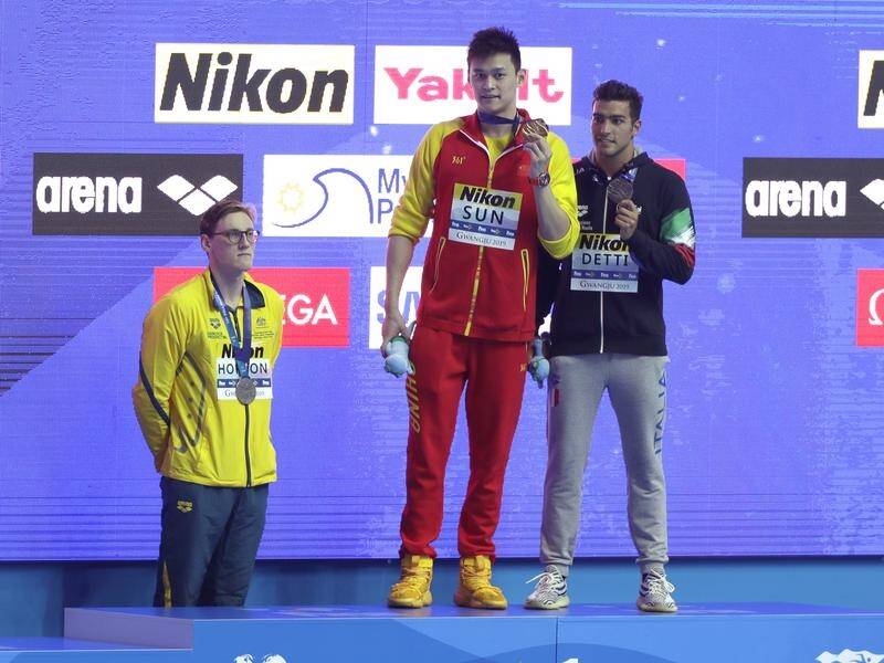 Sun Yang (C) holds up his gold medal as silver medalist Mack Horton (L) stands away from the podium.