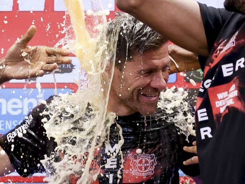 Leverkusen coach Xabi Alonso is doused with beer by his players after their title win. (AP PHOTO)