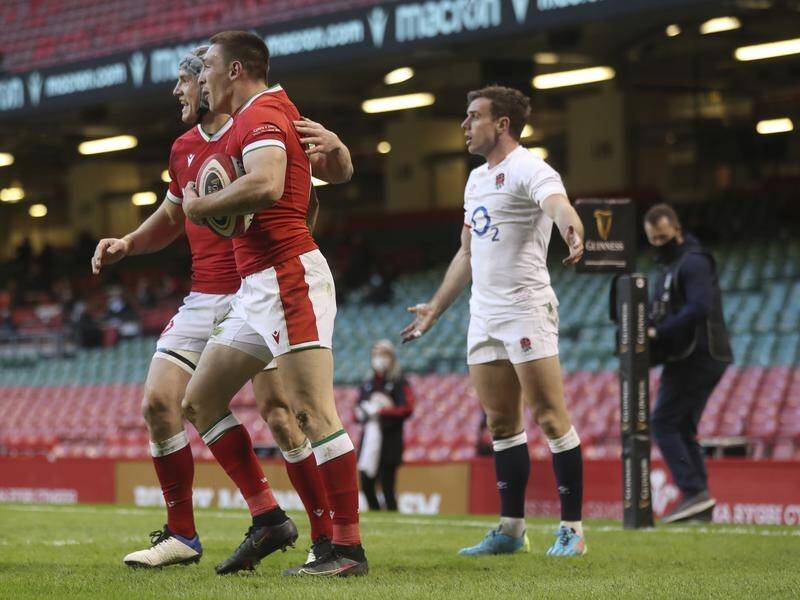 Wales' Josh Adams celebrates his try as England's bemused George Ford wonders how it was allowed.