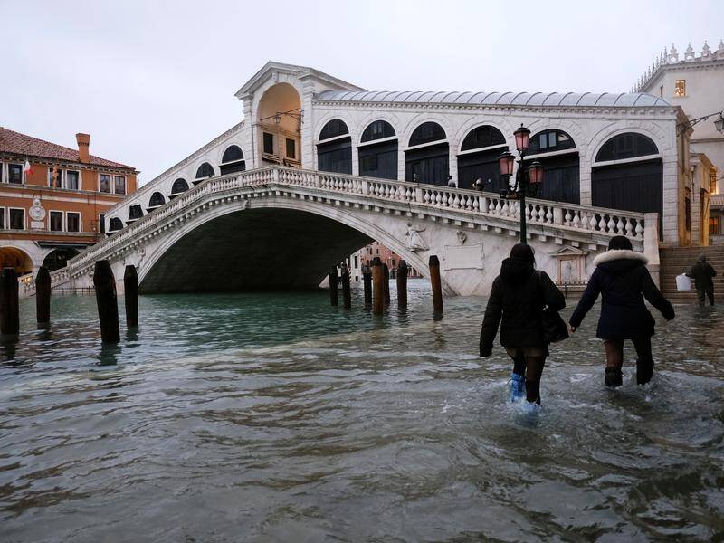 People walk past the Rialto Bridge in Venice during flooding following heavy rains.