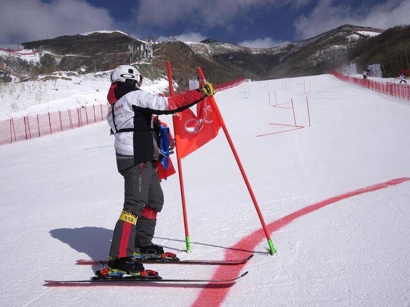 Course workers remove the gates after the postponement of the mixed team parallel skiing event.