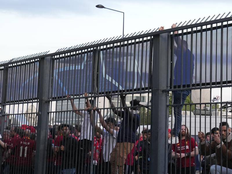 Fans climb on the Stade de France fence at the delayed Champions League final.