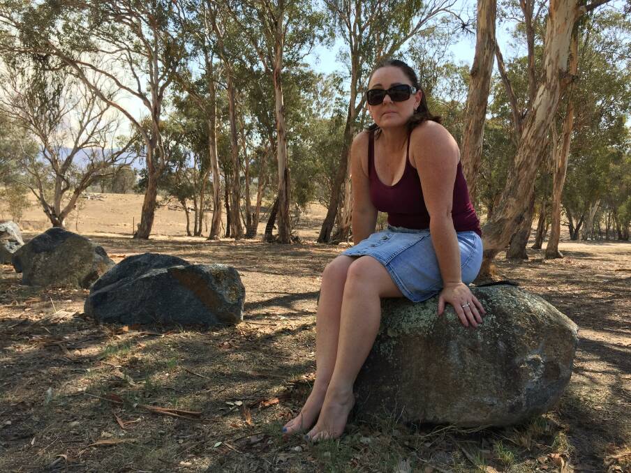Angela Warren sits onthe rock and just looks at the fire across the bush. Picture: Steve Evans