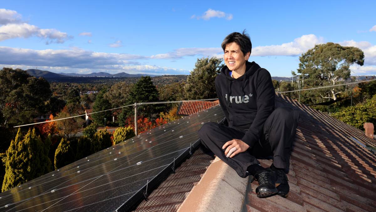 Sue Chong on the roof of her house in Chapman that had solar panels installed as part of the ACT government's Sustainable Household Scheme. Picture by James Croucher