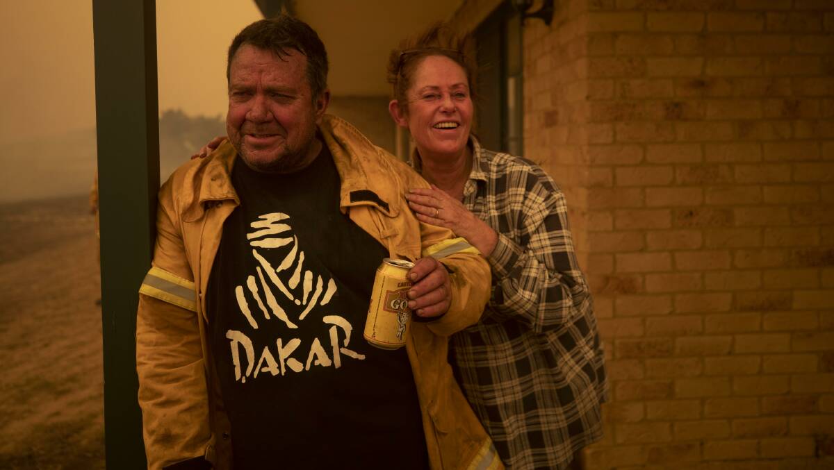 A cold beer in celebration. Laurence and Claire Cowie after defending their home from a fast-moving fire on Bumbalong Road, Bredbo North. Picture: Getty Images
