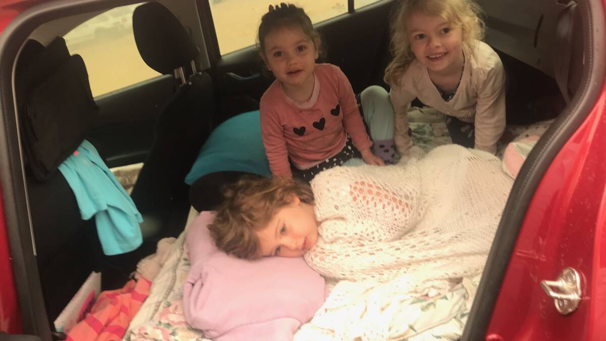 Evie Pronesti (lying down), Sophie Crumpton (back left) and Ella Crumpton sleeping in the car at Narooma before escaping to Queanbeyan.