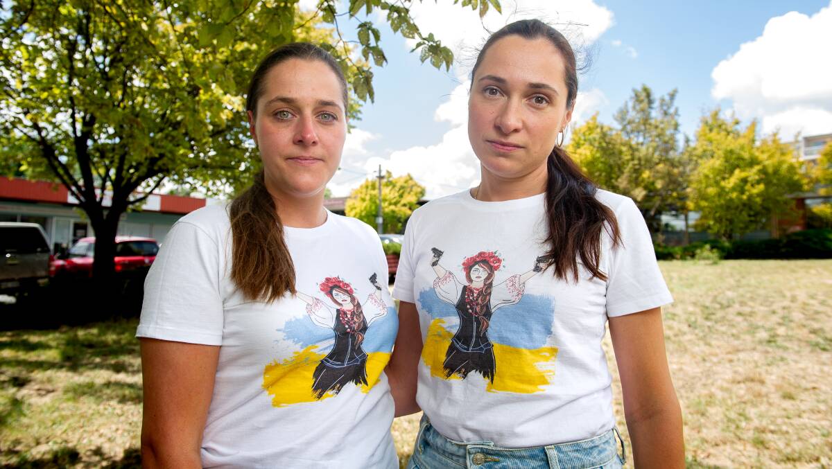 Yustyna (left) and Yaryna wear t-shirts in Canberra embalzoned with the Ukrainian flag and a woman holding two guns aloft. Picture by Elesa Kurtz