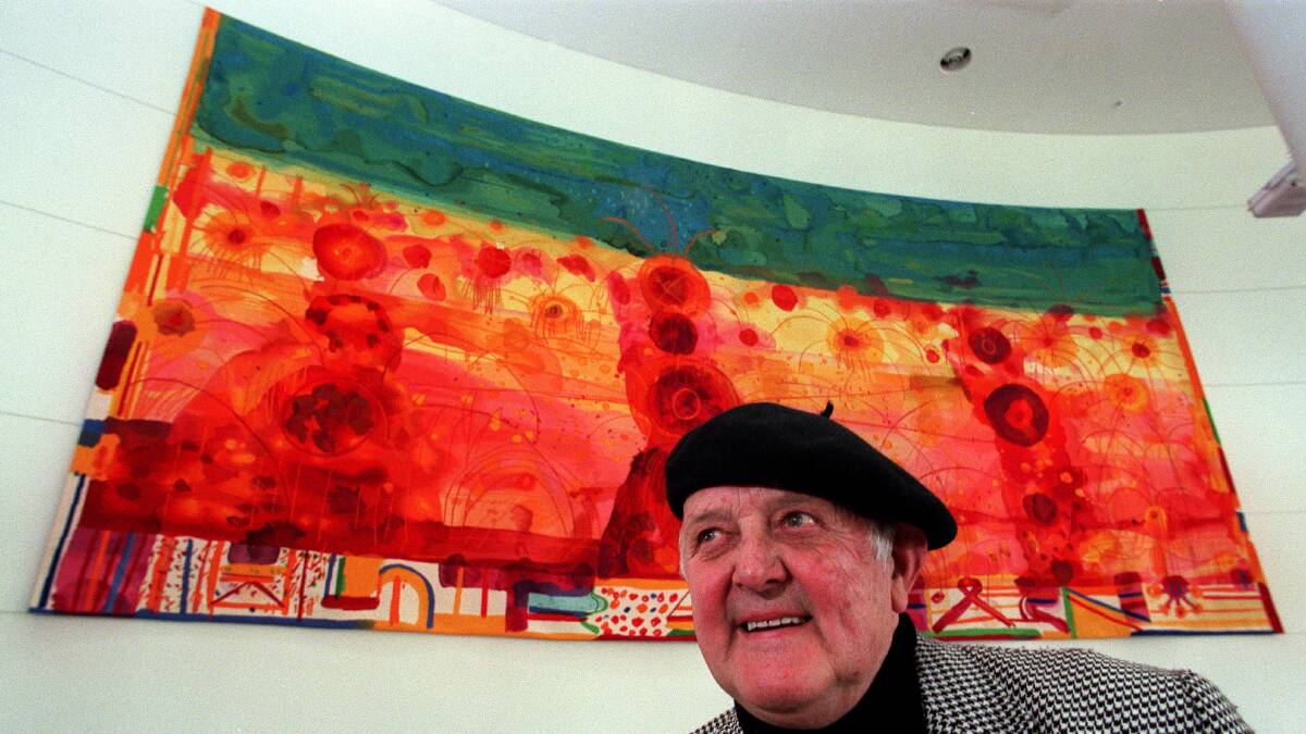 John Olsen in his trademark Spanish beret in front of his painting which hung in the foyer of the DFAT building. Picture supplied