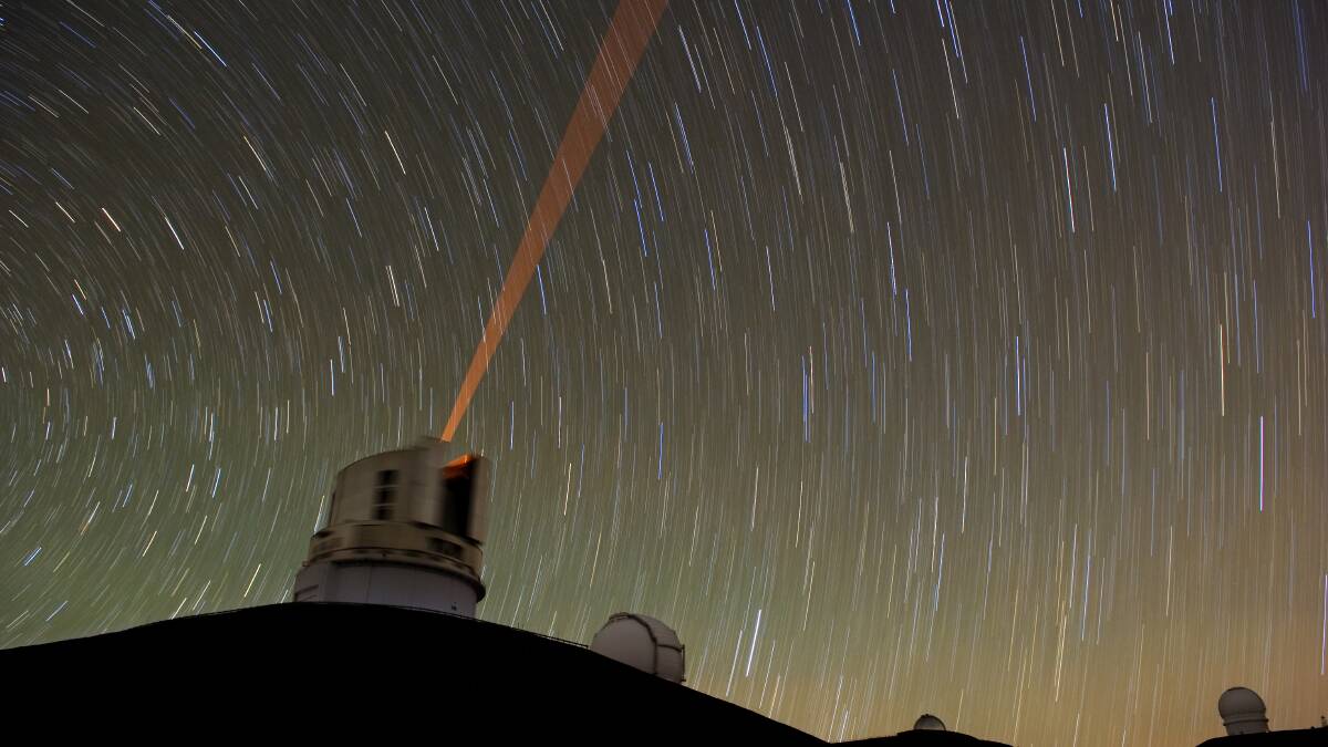 A long-exposure photograph of the guide star laser in use at the Mauna Kea Observatory in Hawaii. Picture: Shutterstock