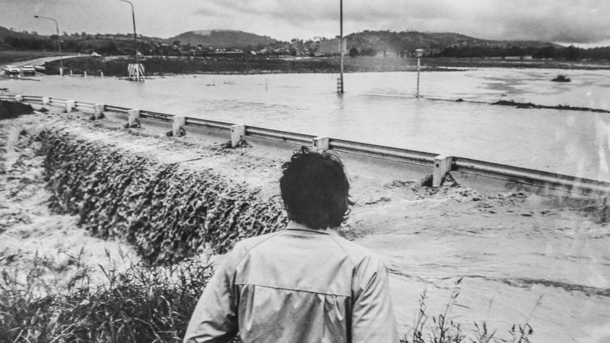 A passerby stands unable to cross the flooded Yarra Glen intersection during the Woden floods. Picture: Canberra Times archives