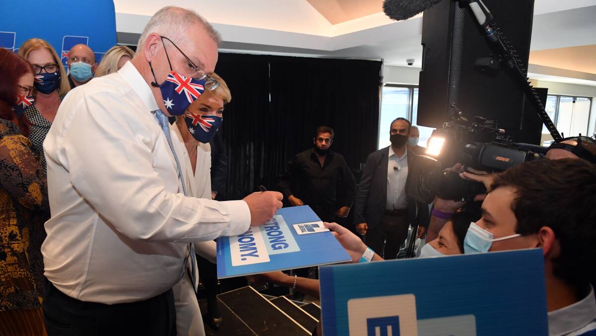 Prime Minister Scott Morrison signs posters at a Liberal Party rally in Perth on Tuesday. Picture: AAP