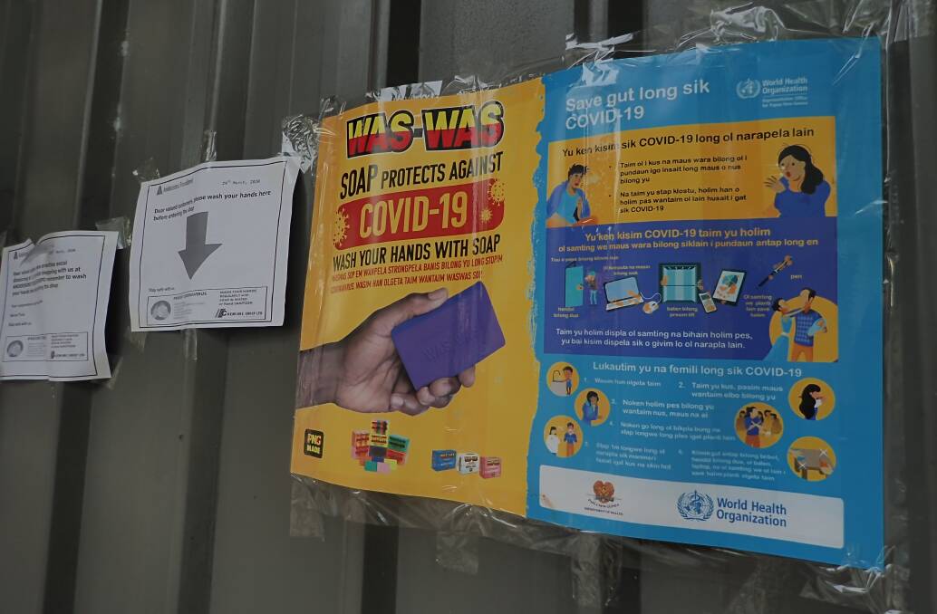 Posters in front of a PNG store offer advice on COVID-19 prevention. Picture: Shutterstock