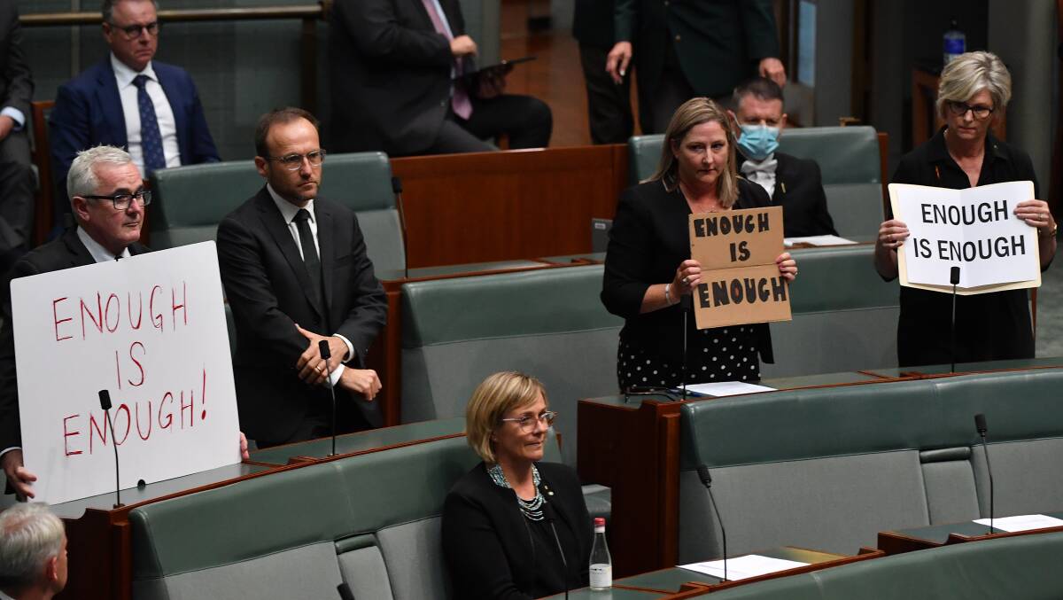 Crossbenchers hold up signs reading 