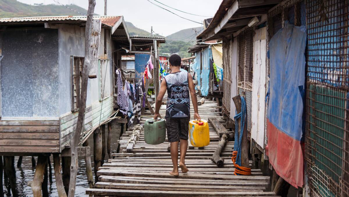 A young man carries jerrycans filled with water on a floating village in Port Moresby, Papua New Guinea. Picture: Shutterstock