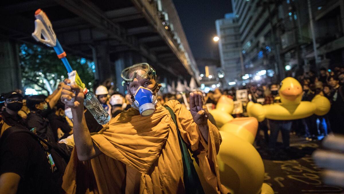 A Thai Buddhist monk wearing a gas mask and holding a water gun gives the three-fingered salute during an anti-government demonstration in Bangkok. Picture: Getty Images