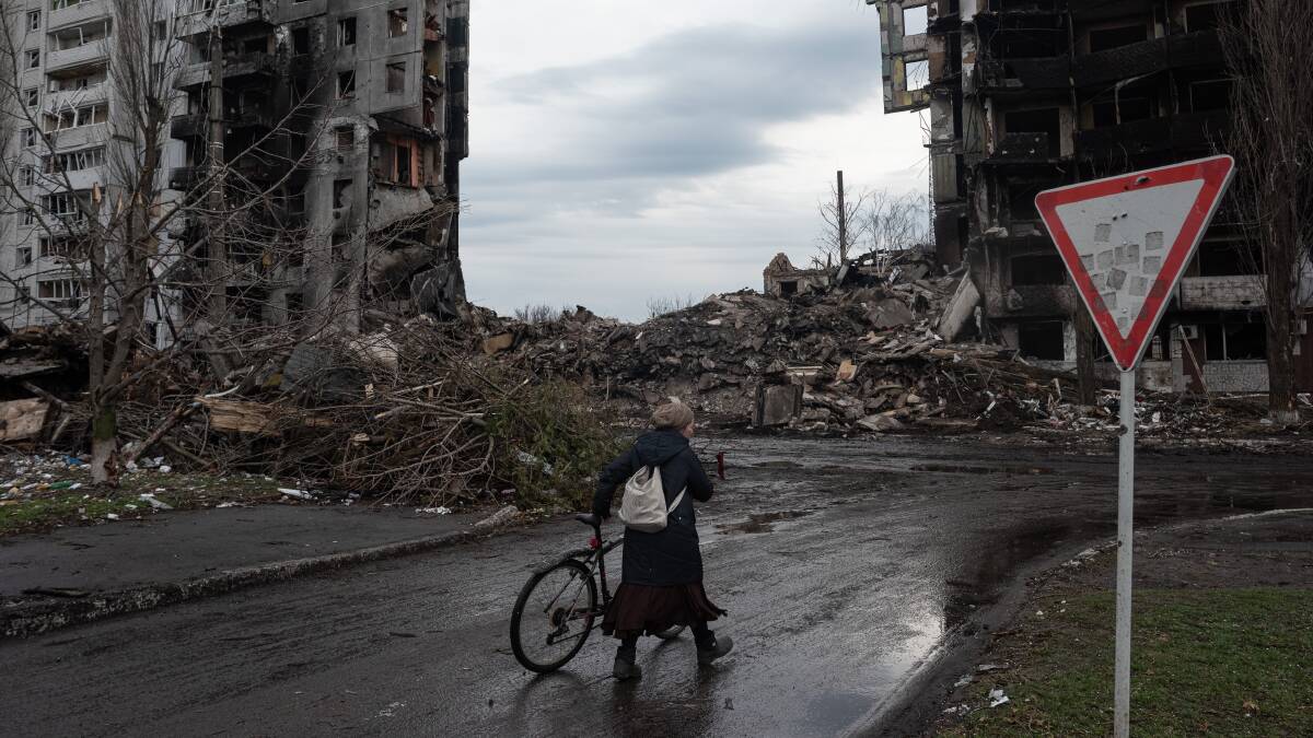 A woman pushes her bicycle in front of a destroyed apartment building in Borodianka, Ukraine, on Saturday. Picture: Getty Images
