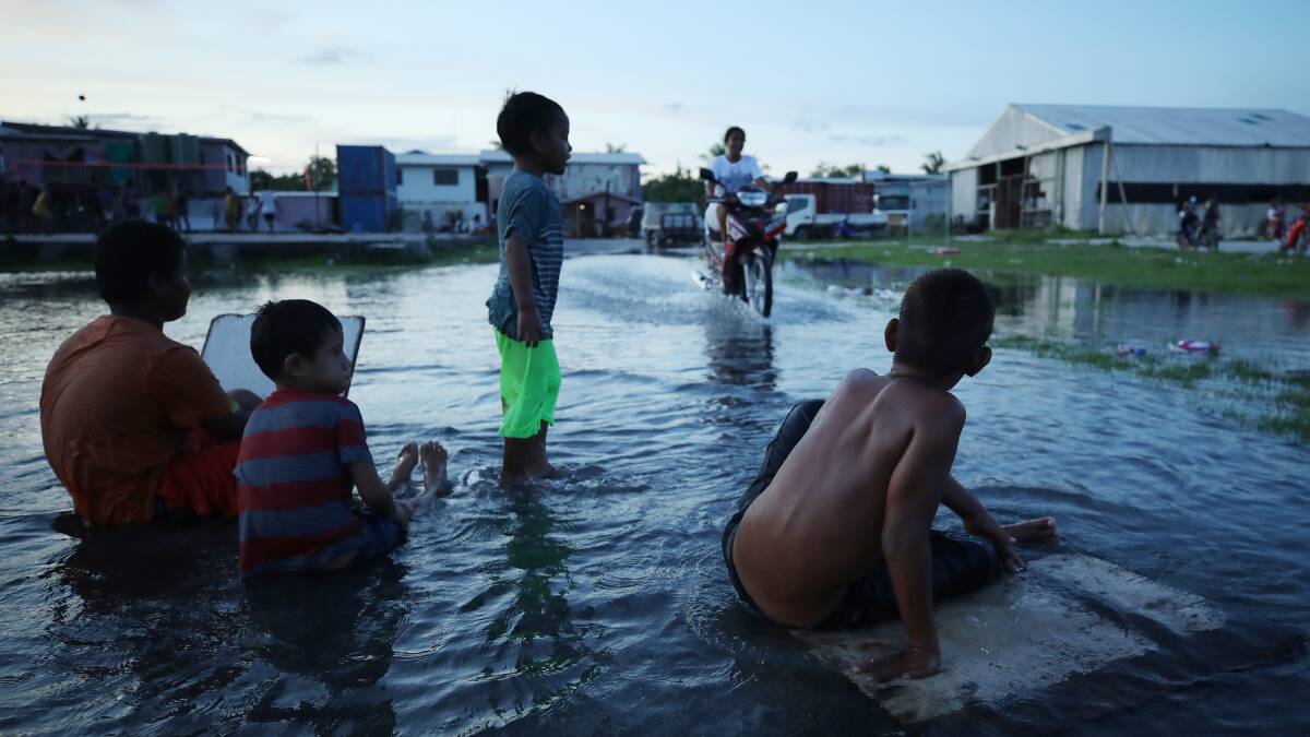 Boys play in floodwater occurring around high tide at an area near the airport in Funafuti, Tuvalu. Picture: Getty Images