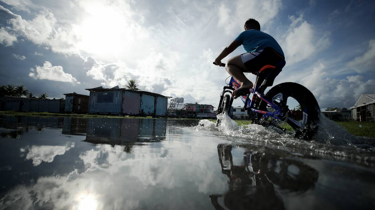 A boy rides his bike through floodwaters near the airport in Funafuti, Tuvalu. The low-lying nation has been classified as extremely vulnerable to climate change. Picture: Getty Images