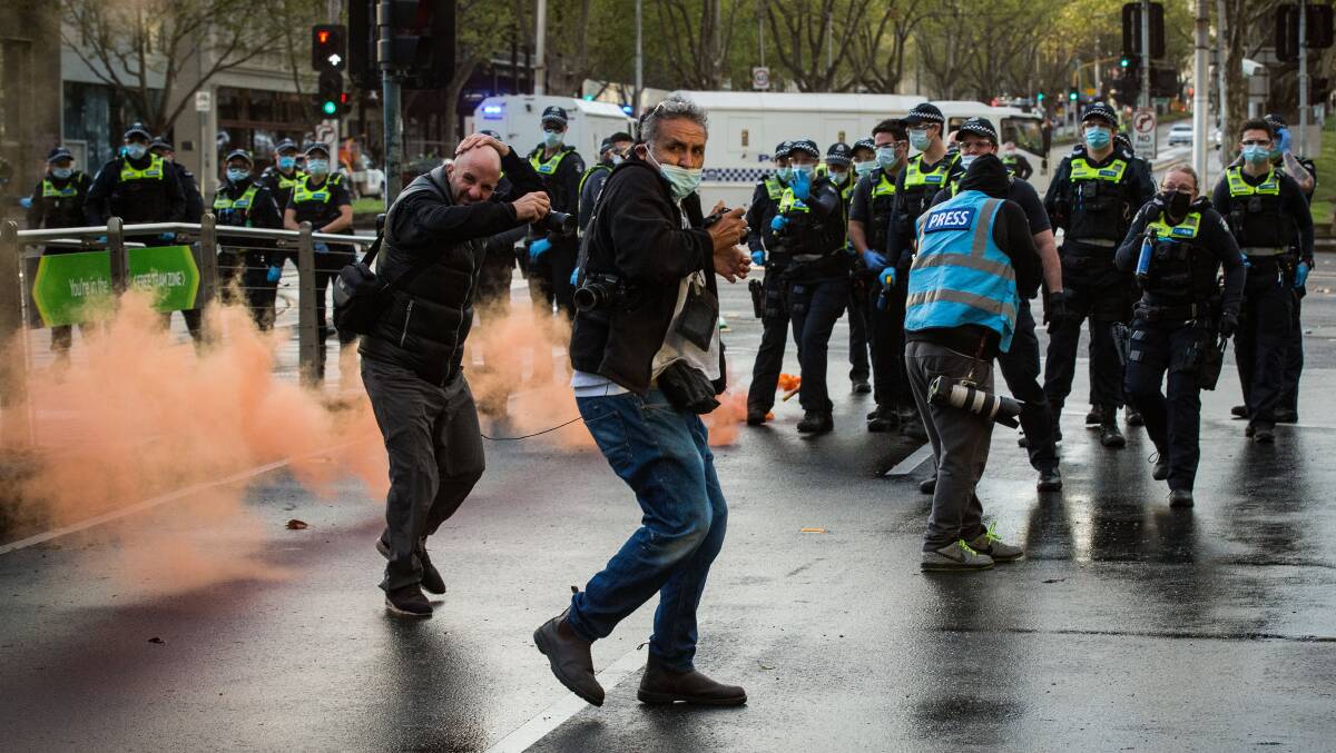 Members of the media look for cover as protesters throw bottles and flares in Melbourne this week. Picture: Getty Images