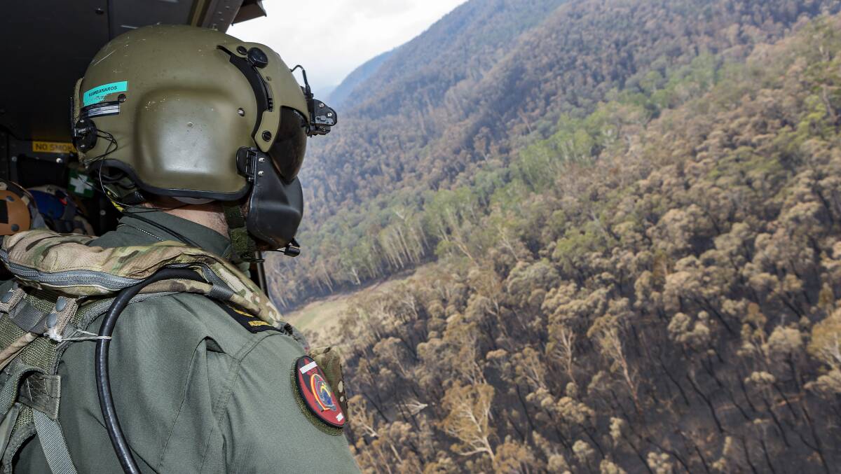 A Royal Australian Navy loadmaster views the devastation in Namadgi National Park from an MRH-90 helicopter. Picture: Department of Defence