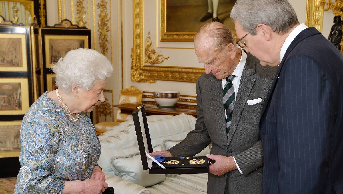 Queen Elizabeth II presents her husband, Prince Philip the Duke of Edinburgh, with the Insignia of a Knight of the Order of Australia at Windsor Castle, accompanied by Australia's then-high commissioner Alexander Downer. Picture: Getty Images