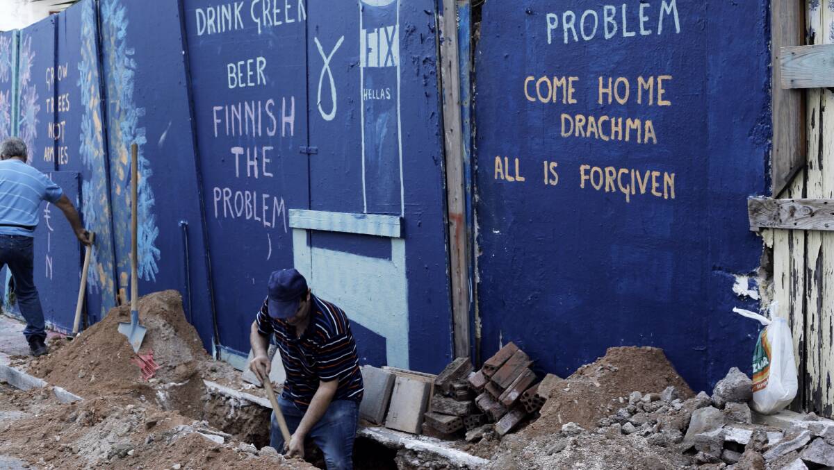 An Athens construction worker works under a sign lamenting the death of Greece's pre-euro currency. In the wake of the financial crisis, the Greek government had to enact severe austerity measures to meet terms laid out by international lenders. Picture: Getty Images