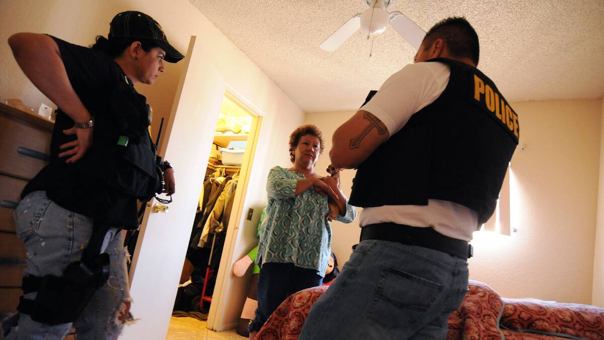 Police question a woman at a house in Nogales, Arizona, about drugs or weapons a dealer might have hidden. Picture: Getty Images