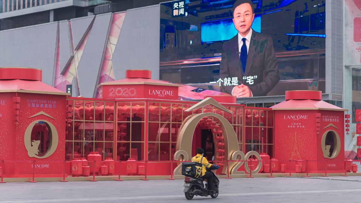 A motorcyclist in Chengdu drives past a screen warning people not to travel to Wuhan. Picture: Shutterstock