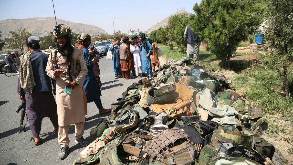 Taliban fighters stand alongside the discarded belongings of Afghan National Army soldiers in Kabul on Monday. Picture: Getty Images