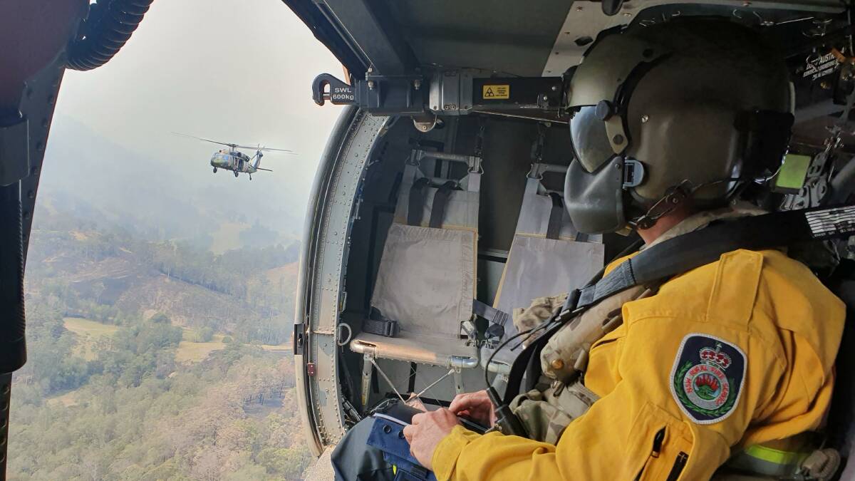 A member of the NSW Rural Fire Service is flown in a 6 Aviation Regiment Blackhawk helicopter during firefighting efforts in November. Picture: Department of Defence