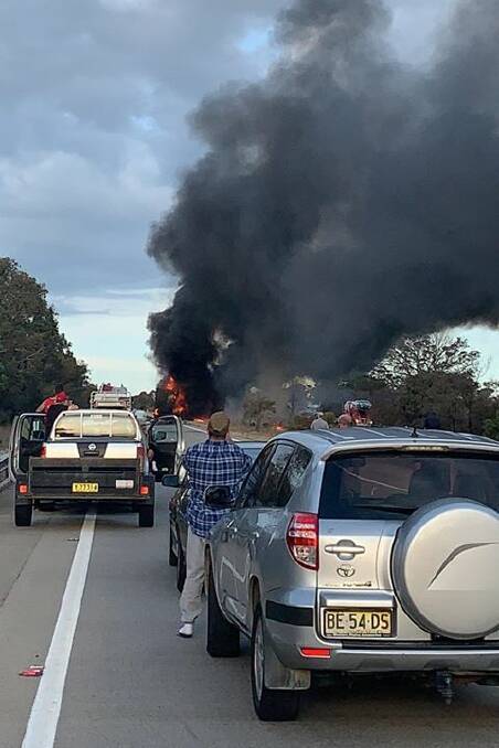 Cars stop as the trucks are engulfed by flames.