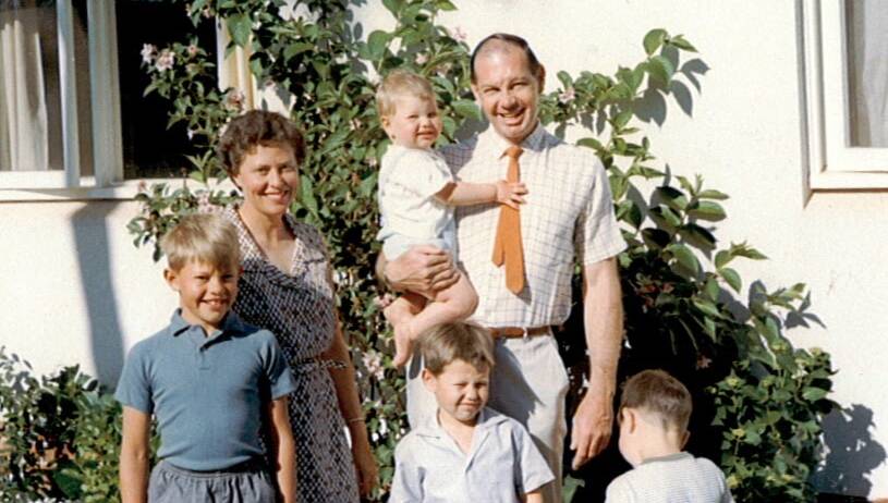 James Wallner in the arms of his father at the family's home in Campbell, where he was exposed to Mr Fluffy asbestos. His brother Bruce is on the far left. Picture: Supplied