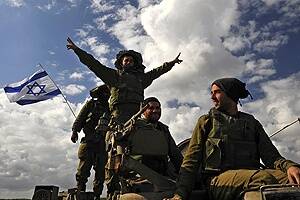 An Israeli soldier gestures from atop an armoured personnel carrier after crossing back into Israel from the Gaza Strip.