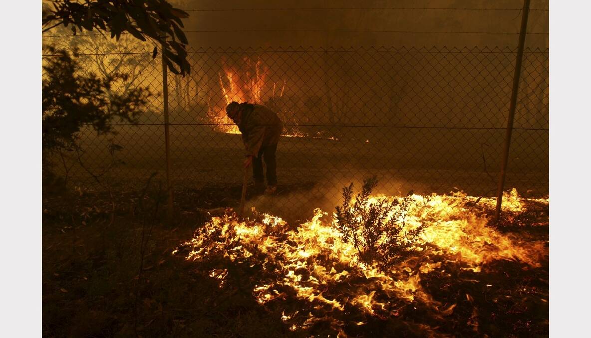 A resident protects his property as an out of control bushfire threatens four homes near Newnes train station. Photo: Wolter Peeters