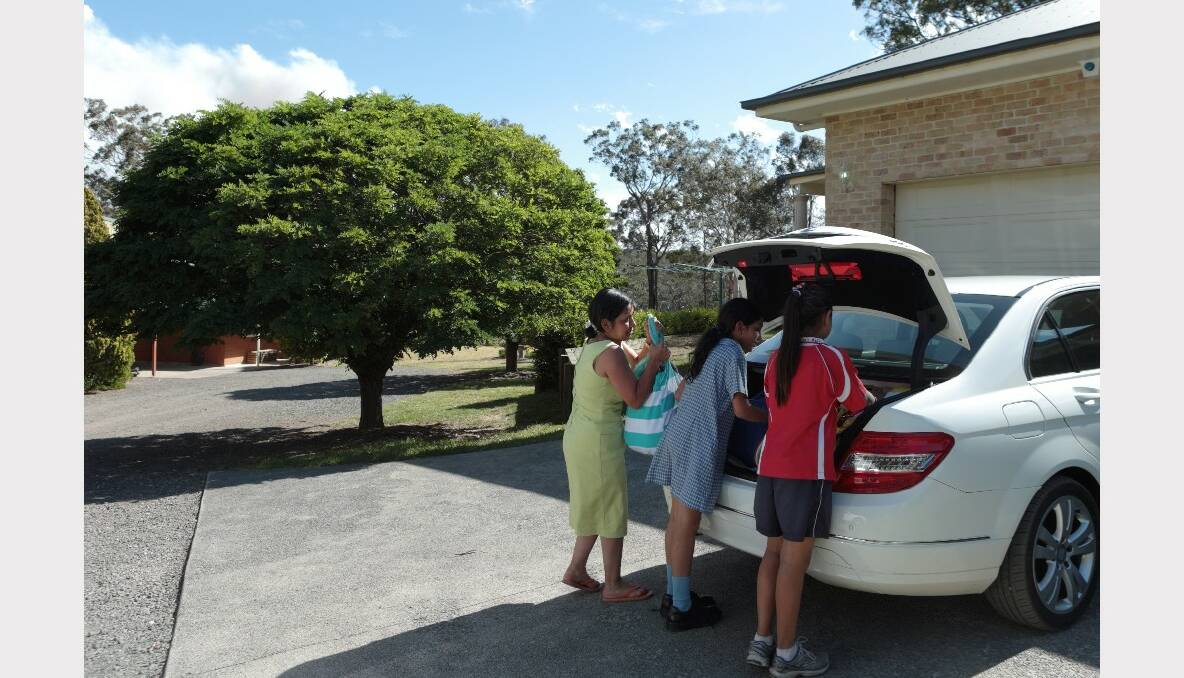 Maria Misfud with daughters (red) Stephanie and Natalie at their home on Emma Lane in Wilton putting personal items in their car as smoke from the Southern Highlands blows overhead. Photo: Illawarra Mercury.